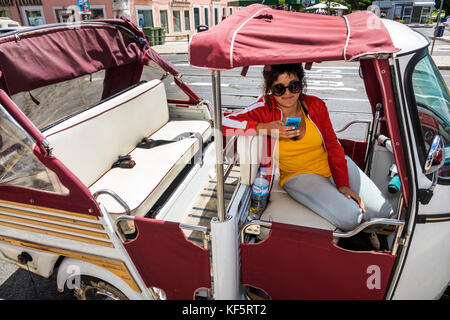 Lisbon Portugal,Belem,historic district,Rua de Belem,tuk-tuk,tricycle,cycle rickshaw,adult adults woman women female lady,driver,waiting,smartphone sm Stock Photo