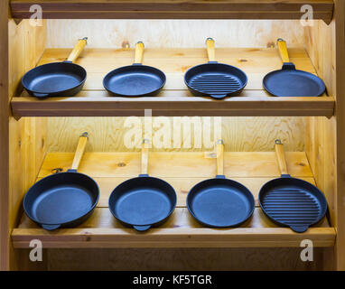 Frying pans on wooden shelf, cooking tools Stock Photo