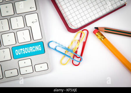 Outsourcing concept. Computer keyboard on a white office desk with various items Stock Photo