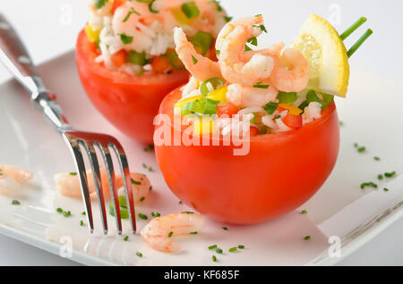 Stuffed, fresh tomatoes with shrimps, rice, bell peppers, spring onions, lemon, chives and parsley Stock Photo