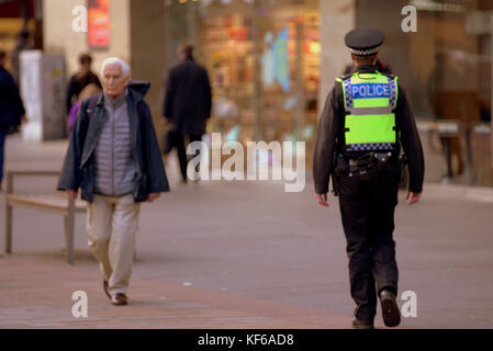 policeman police scotland  on the street walking the beat viewed from behind Stock Photo