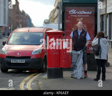 Royal Mail postman collecting letters street red postbox van talking to customer christmas poster Stock Photo