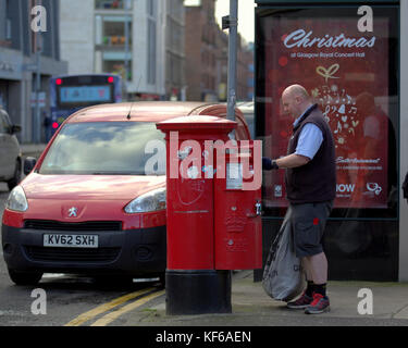 Royal Mail postman collecting letters street red postbox van talking to customer christmas poster Stock Photo