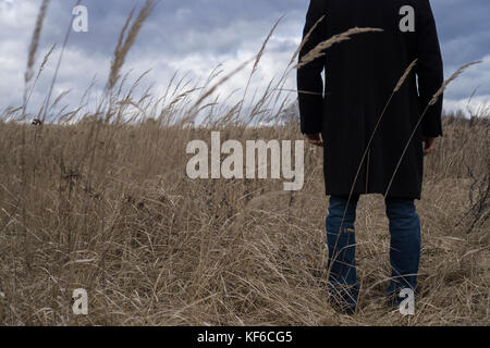 Back close up of a man wearing a coat standing in a field Stock Photo