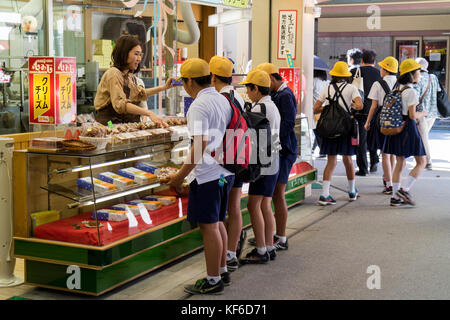 Miyajima, Japan -  May 26, 2017:Group of school children in uniform buying gifts and candy in Miyajima on a school trip Stock Photo
