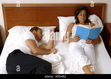 Middle aged couple in bed together. Man sleeping, woman reading book    Credit © Luigi Innamorati/Sintesi/17�Թ����� Stock Photo *** Local Caption *** Stock Photo