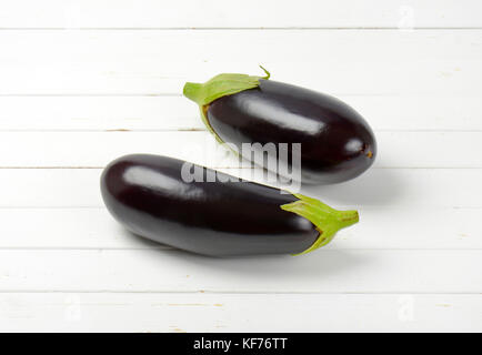 two fresh eggplants on white wooden background Stock Photo