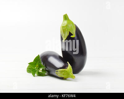 two fresh eggplants and sage on white wooden background Stock Photo