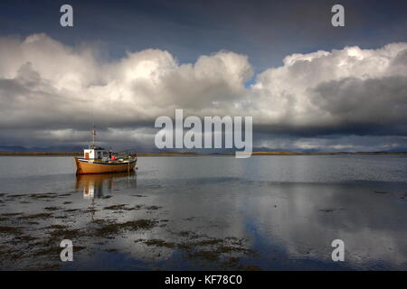 Scenic view of the Atlantic ocean over cloudy skies in Clew Bay Westport Ireland County Mayo. Yellow boat reflection  with Ocean & hills in distance. Stock Photo