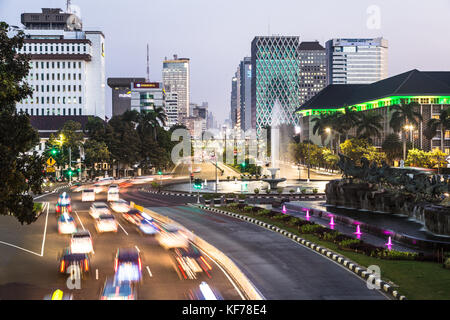 JAKARTA, INDONESIA - JUNE 8, 2017: Traffic, captured with blurred motion, rushes along the Thamrin avenue in the heart of Jakarta downtown district in Stock Photo