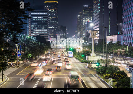 JAKARTA, INDONESIA - JUNE 8, 2017: Traffic, captured with blurred motion, rushes along the Thamrin avenue in the heart of Jakarta downtown district in Stock Photo