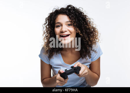 Upbeat curly-haired woman playing video games Stock Photo