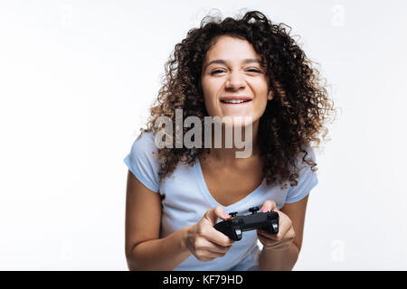 Cute curly-haired woman being immersed into playing video game Stock Photo
