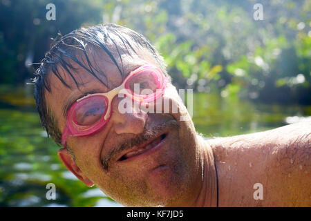 Crazy nerd hilarious guy with diving goggles in a lake Stock Photo