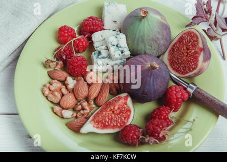 Serving the table, fresh figs, fruits, berries, cheese, nuts on a white wooden background Stock Photo