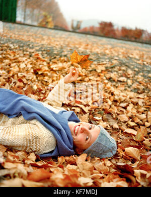 USA, California, portrait of happy young woman lying on autumn leaves Stock Photo