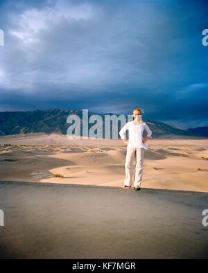 USA, California, young woman standing on sand dune, Stovepipe Wells, Death Valley National Park Stock Photo