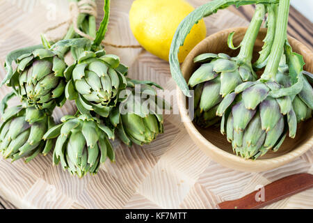 Two artichoke bouquets on kitchen table among some kitchen items. Top view Stock Photo