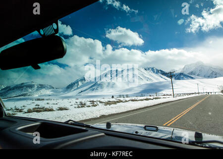 USA, California, Mammoth, snow covered mountain ranges surround the road leading out to the Mammoth Hot Springs Stock Photo