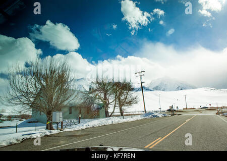 USA, California, Mammoth, snow covered mountain ranges surround the road leading out to the Mammoth Hot Springs Stock Photo