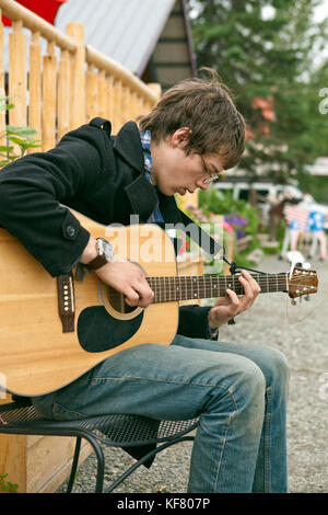USA, Alaska, Talkeetna, a young man Ian Merkley plays the guitar on the street in town Stock Photo