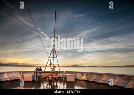 CANADA, Vancouver BC, A couple watches the sunset off the Holland America cruise ship, the Oosterdam, cruising the Inside Passage from Vancouver BC to Stock Photo