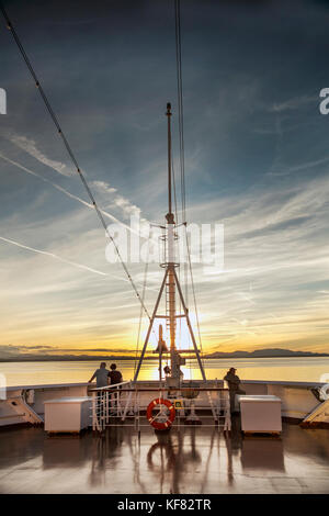 CANADA, Vancouver BC, A couple watches the sunset off the Holland America cruise ship, the Oosterdam, cruising the Inside Passage from Vancouver BC to Stock Photo