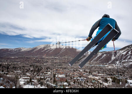 USA, Colorado, Aspen, skier getting air on a trail called Corkscrew with the town of Aspen in the distance, Aspen Ski Resort, Ajax mountain Stock Photo