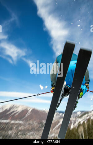 USA, Colorado, Aspen, skier getting air on a trail called Corkscrew with the town of Aspen in the distance, Aspen Ski Resort, Ajax mountain Stock Photo