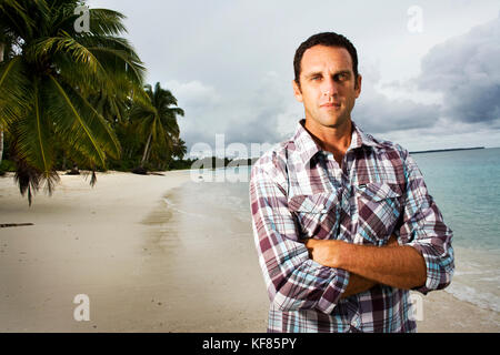 INDONESIA, Mentawai Islands, Kandui Resort, portrait of mid adult man standing on beach with arms crossed Stock Photo