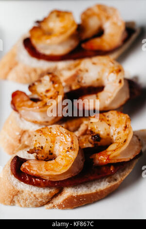 Tasty chorizo and grilled shrimp canapes on toasted italian bread Stock Photo