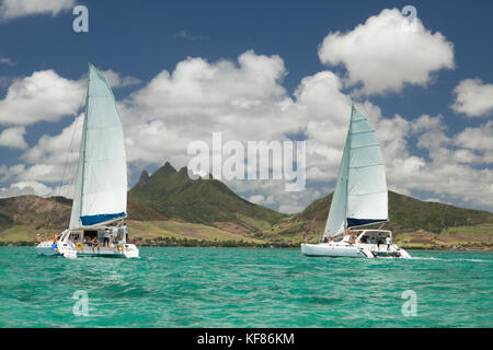 MAURITIUS, Trou D'eau Deuce, tourists sail in the Indian Ocean off the East coast of Mauritius with the 4 Sisters Mountains in the background Stock Photo