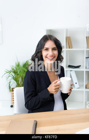 pregnant businesswoman with cup of hot drink Stock Photo