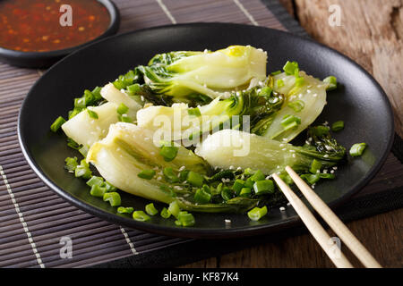 Chinese fried bok choy with sesame and sweet chili sauce close-up on the table. horizontal Stock Photo