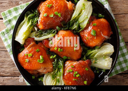 Fried chicken thighs with bok choy and green onions close-up on a plate. Horizontal top view from above Stock Photo