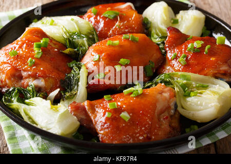 Delicious fried chicken thighs with bok choy and green onions close-up on a plate. horizontal Stock Photo