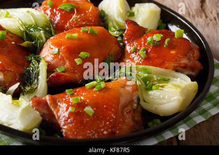 Fried chicken thighs with bok choy and green onions close-up on a plate. horizontal Stock Photo
