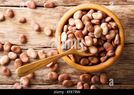 Organic dried broad beans close-up in a wooden bowl on a table. horizontal top view from above Stock Photo