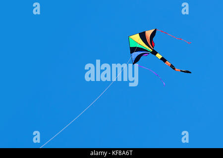 Rainbow kite flies in blue sky sunny day Stock Photo