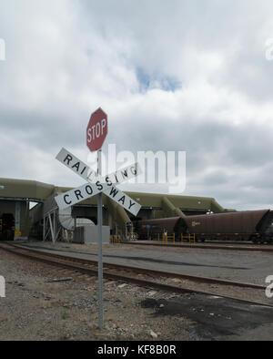 Rail wagons loaded with coal entering the unloading shed,image showing a railway crossing and red stop sign at Newcastle, New South Wales, Australia. Stock Photo