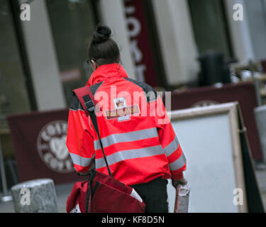 Royal Mail postman postwoman delivering letters street doorway costa coffee Stock Photo