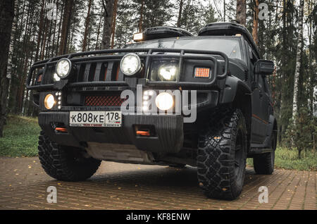 Saint-Petersburg, Russia - October 8, 2017: Black Hummer H2 car stands on rural parking lot in Russian countryside, close up photo, headlights on Stock Photo