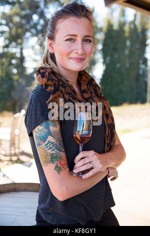 USA, Oregon, Willamette Valley, portrait of a beautiful young woman with a glass of red wine at the tasting room at Sotor Vineyards and Winery, Carlto Stock Photo