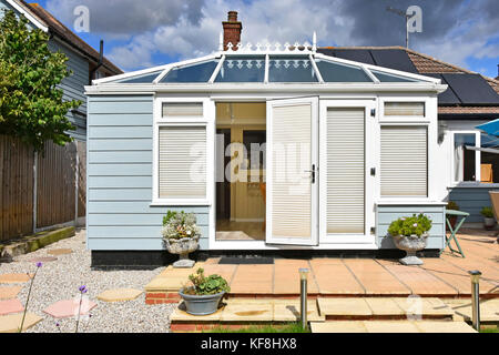 Back view of brick built bungalow solar panels & modern conservatory facing south extending into back garden blinds fitted to reduce summer heat UK Stock Photo