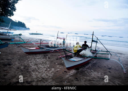 PHILIPPINES, Palawan, Sabang, fishermen repair their nets and repair their boats at the main beach in the town of Sabang Stock Photo