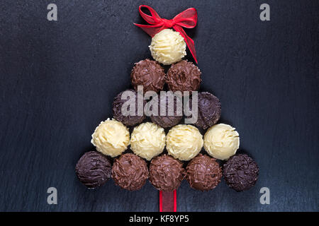 Chocolate truffles shape Christmas tree on black stone table top view Stock Photo