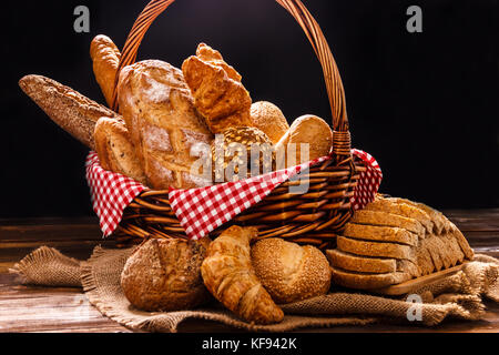 Bakery Assortment on wooden table on dark background. Still Life of variety of bread with natural morning light.. Stock Photo