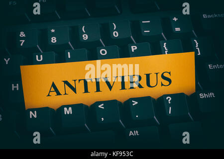 Yellow paper note on black keyboard with writing Antivirus. Close up. Stock Photo
