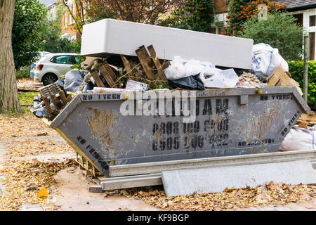 A full waste skip with an old mattress on top of it. Stock Photo