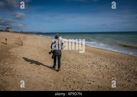 Lone mature woman walking on beach at Norman's Bay, UK. Stock Photo